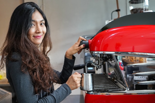 Asian women Barista smiling and using coffee machine in coffee shop counter 