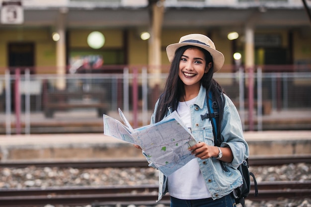 Asian women be smile with map Travel Holiday at the train station with a traveler Relaxation Concept