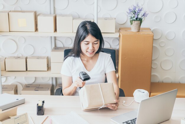 Asian Women business owner working at home with packing box on workplace