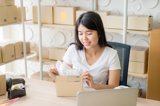 Asian Women business owner working at home with packing box on workplace