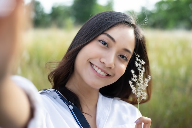 Asian women happy smile  taking photos and Selfie on relaxing time at  meadow and grass