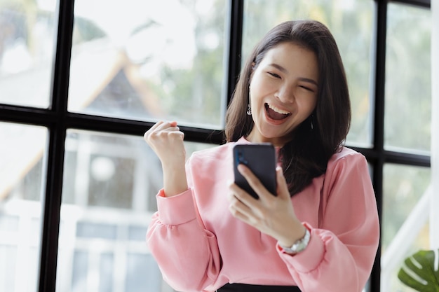 Asian women look at information on mobile phones and show joyful expressions run by a young talented woman The management concept runs the company of female leaders to grow the company