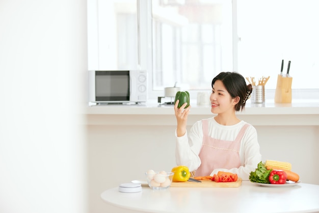 Asian women relax at the kitchen table with fresh fruit vegetables