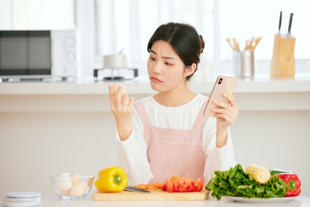 Asian women relax at the kitchen table with fresh fruit vegetables