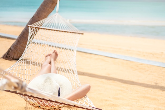 Asian women relaxing in hammock summer holiday on beach