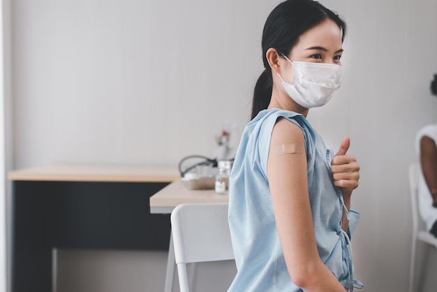 Asian women showing adhesive bandage plaster on arm after getting vaccinated