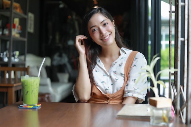 Asian women smiling and happy Relaxing with green tea in a coffee shop 