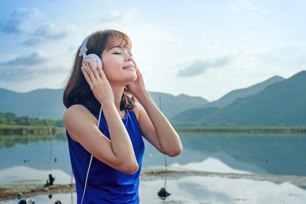 Asian women wear sport shirt  with headphones listening to music and relaxing at outdoors