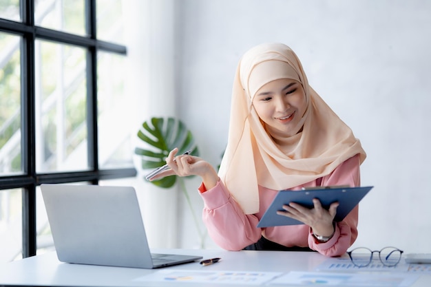 Asian women wearing hijab sitting in the office of a startup company managed and operated by a young talented working woman The management concept drives the company of women leaders to grow