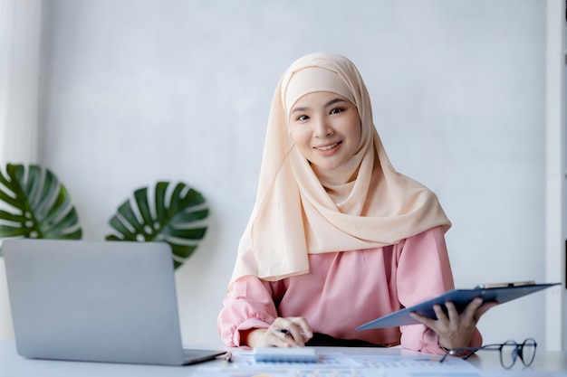 Asian women wearing hijab sitting in the office of a startup company managed and operated by a young talented working woman The management concept drives the company of women leaders to grow