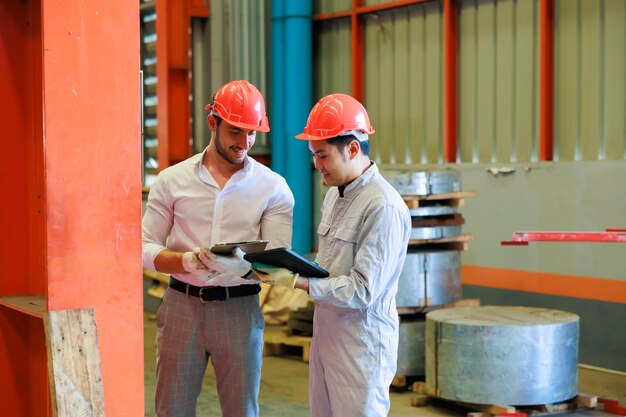 Asian worker and Electrician engineer tests electrical installations on laptop and digital tablet computer at Heavy Industry Manufacturing Factory