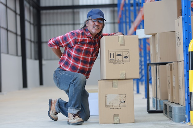 Asian worker man hurt his back lift heavy box in factory