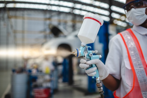 Asian workers stand to hold a spray gun in protective clothing