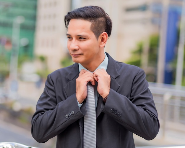 Asian young business man in front of the modern building in downtown .Concept of young  business people