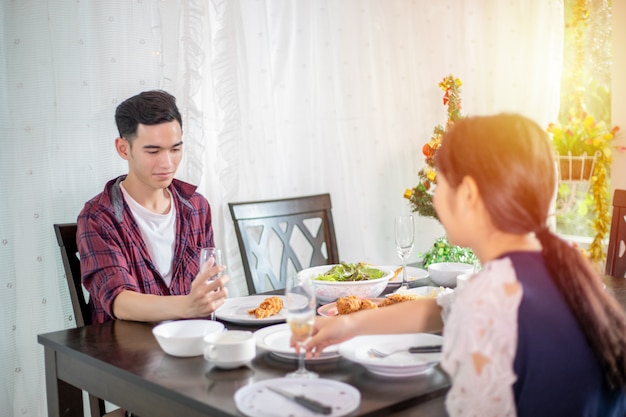 Asian young couple enjoying a romantic dinner  evening drinks while sitting at the dinning table on the kitchen together