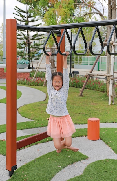 Asian young girl child having fun playing on equipment at a playground