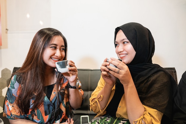 Asian young girls chatting and enjoy cup of coffee while sitting in a coffee shop