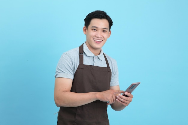 Asian young handsome man in waiter uniform welcome guest and take order