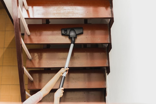 Asian young housekeeper hoovering stairwell in a house