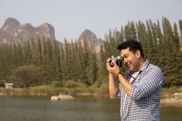 Asian young man in blue shirt with cute puppy dog camping on the lake hill mountain view happy and enjoy life