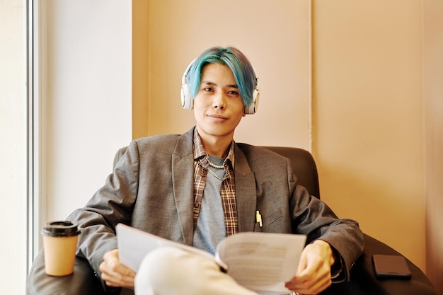 Asian young man looking at camera relaxing in office