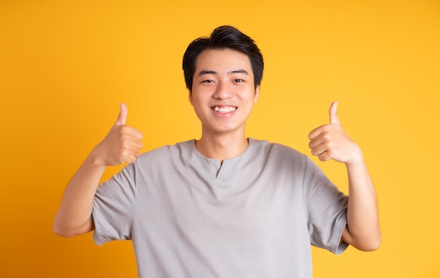 Asian young man posing on a yellow background