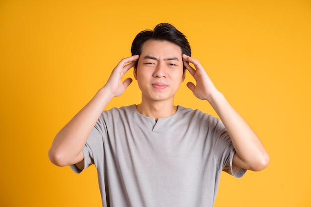 Asian young man posing on a yellow background