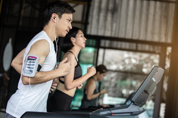 Asian young man in sportswear running on treadmill at gym