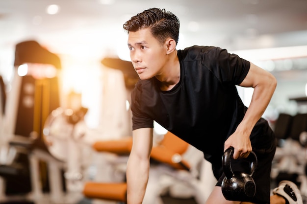 Asian young man using dumbbell Pushing up exercise at gym for good healthy in fitness Lifestyle and sport exercise concept