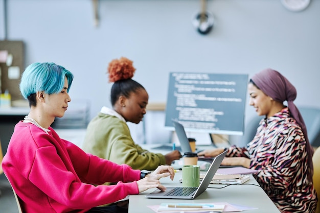 Photo asian young man using laptop in office team in background