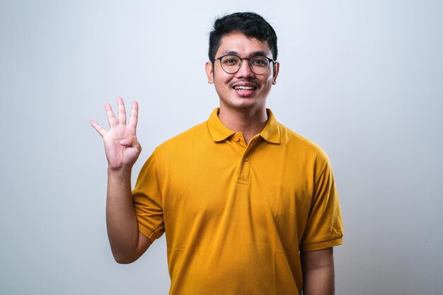 Asian young man wearing casual clothes showing and pointing up with fingers number four while smiling confident and happy over white background