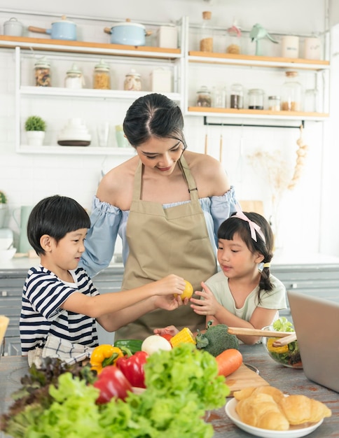 Asian young single mother with son and daughter in kitchen Enjoy family activity together