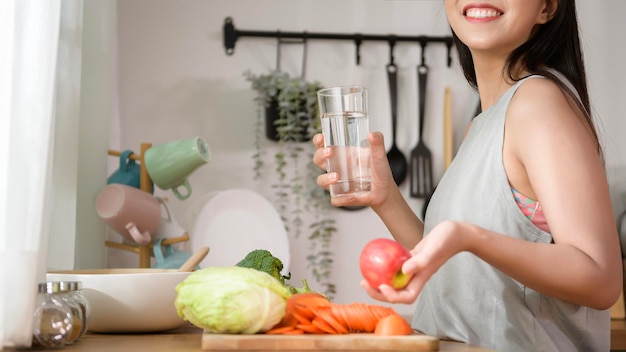 An Asian young woman drinking fresh water in kitchen at home healthy lifestyle concept