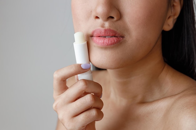 Asian young woman holding hygienic lipstick in studio