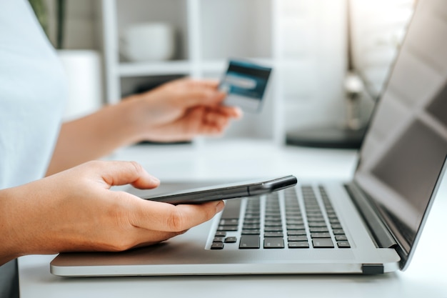 Asian young woman resting and browsing internet with Laptop holding credit card online shopping concept