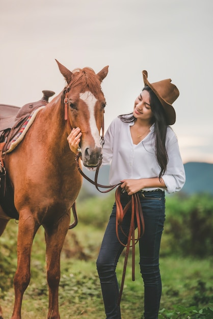 Asian young woman  take care of her blows horse at sunset.