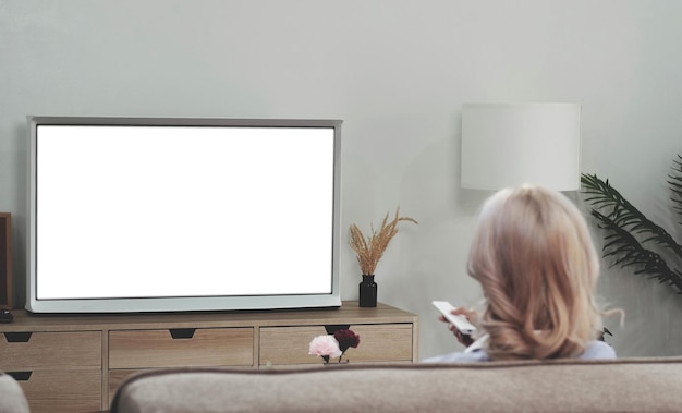 Behind of asian young woman watching white screen TV on the sofa at home