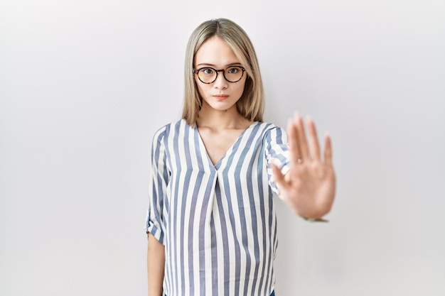 Asian young woman wearing casual clothes and glasses doing stop sing with palm of the hand warning expression with negative and serious gesture on the face