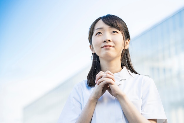 Asian young woman in a white coat in a prayer pose