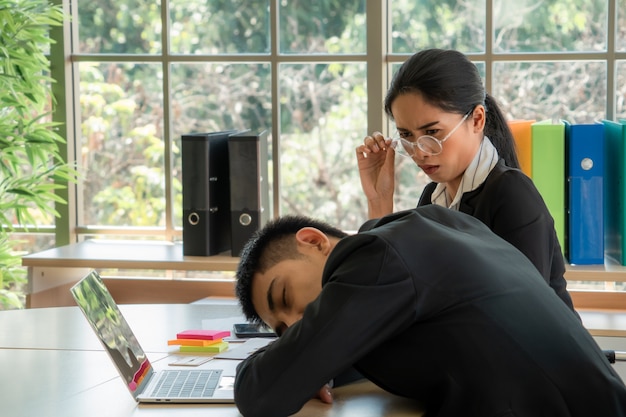 Asian young women feel bored when she see her colleagues sleeping, business concept