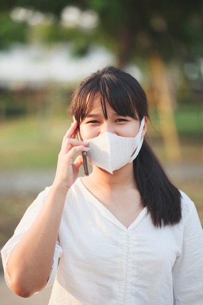 Asian younger woman wearing protection mask talking on mobilephone