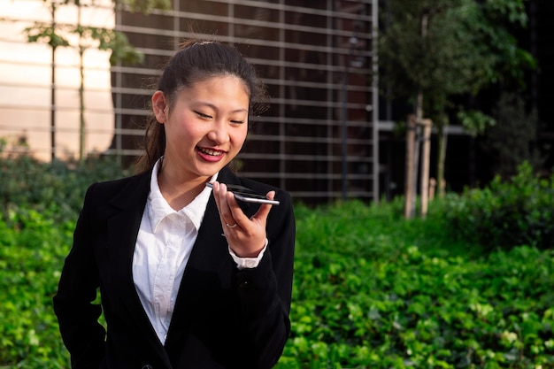 Asiatic woman recording voice message with phone