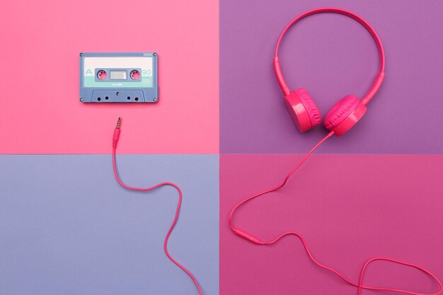 Aside of blue audio cassette on a pink background and pink headphones on a violet background