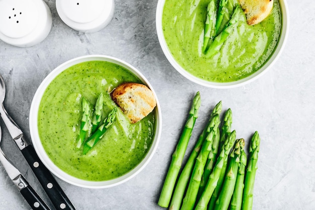 Asparagus cream soup with croutons on gray stone background top view Green summer vegetable soup