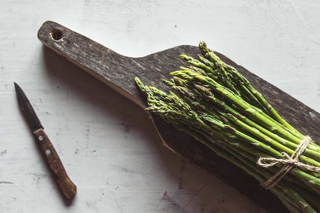 Asparagus on a cut board on an old white background