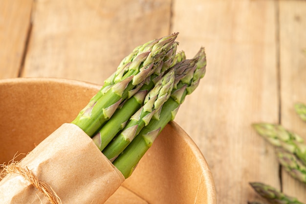 Asparagus in a paper bowl on a wooden table