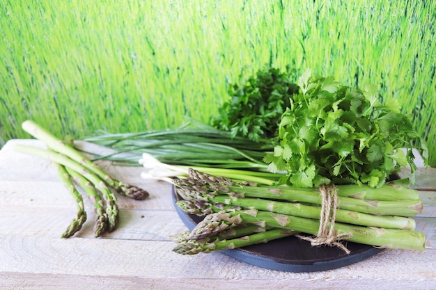 Asparagus radishes and green onions in a wicker basket on a wooden table