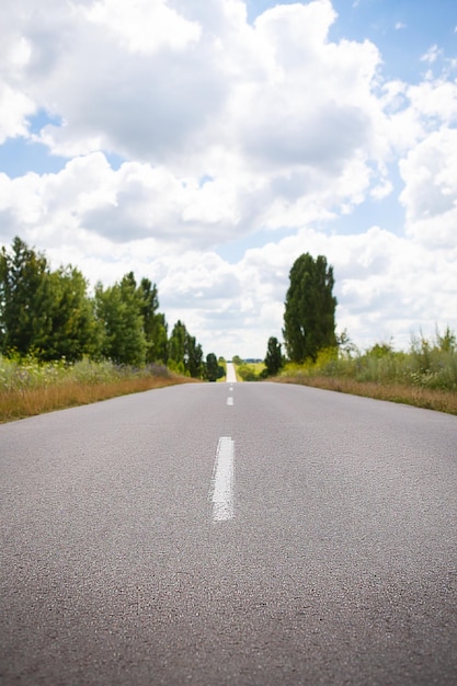 Asphalt flat road between rural fields Summer sunny day beautiful sky