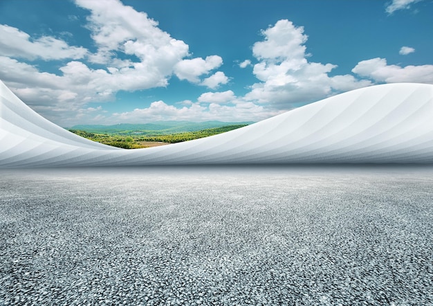 Asphalt ground and curved art building with green mountains blue sky and white clouds background