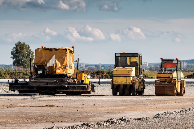 Photo asphalt paver and two tandem rollers for road repair